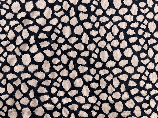 Sandfarbener Jacquard-Strick mit feinem Leo-Muster, zusammengerollt und in Nahaufnahme dargestellt